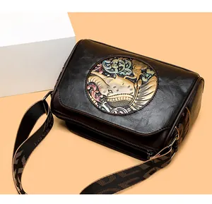 Macro view of vintage black leather pillow bag with colorful elephant relief and woven strap