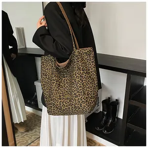 Close-up of leopard print canvas tote bag with metal tag and shoulder strap detail