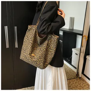 Detail of leopard print tote bag with a gold metal emblem and slim shoulder straps