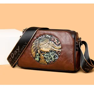 Detail of vintage brown crossbody bag with embossed elephant and floral design