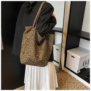 Detail of leopard print tote bag with leather handles and metallic buckle on model