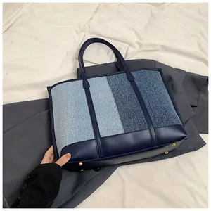 Detailansicht der Kontrast-Tote-Bag mit goldenen Metallfüßen auf weißem Stoffgrund