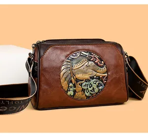 Detail of vintage brown leather bag featuring embossed elephant motif and wide strap