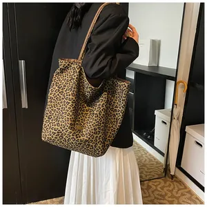 Macro view of leopard print fabric detail and metal emblem on large shoulder tote bag