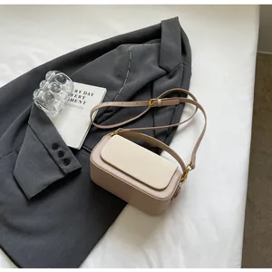 Gros plan sur la texture bicolore et les boucles dorées de ce petit sac carré élégant