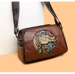 Detailed view of the elephant relief metal plate and vintage textured leather on the bag