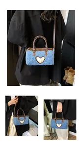 Detail van blauwe teddy barrel bag met hartvormige patch en bruine leren riemen