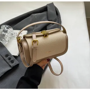 Détail du sac beige bandoulière montrant la texture tissée et le fermoir coquillage doré