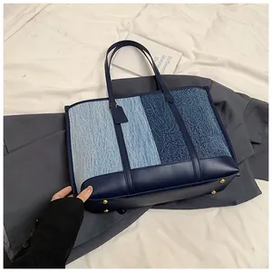 Detail der Denim-Einkaufstasche mit dunkelblauem Lederbesatz und goldenen Nieten