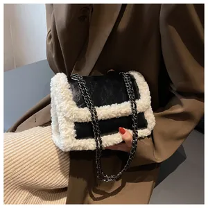 Detail of black leather underarm bag with white faux fur trim and metal chain strap
