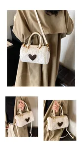 Detail van witte pluche handtas met bruine hartvormige patch en gouden ritssluiting