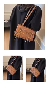 Detailed close-up of brown suede shoulder bag featuring woven edges and bow tassels