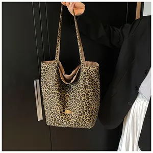 Detail shot of large leopard print tote bag with brown straps and logo patch