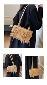 Close-up of khaki suede shoulder bag with ribbon bow and woven texture details