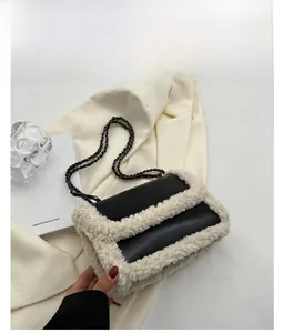 Detail view of black faux leather shoulder bag with white faux fur trim and chain strap