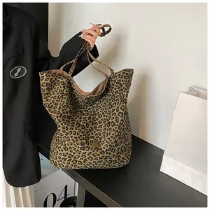 Detail shot of leopard print tote bag featuring a golden oval logo plaque and fabric texture