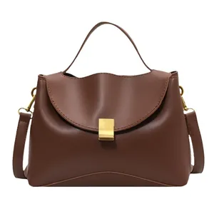 Brown leather handbag with wavy flap and gold square lock in a minimalist style