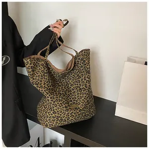 Detail shot of leopard print tote bag with a golden metal logo plate and sturdy handles