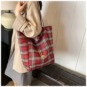 Close-up of a large red plaid tote bag featuring a handmade label on a soft canvas surface