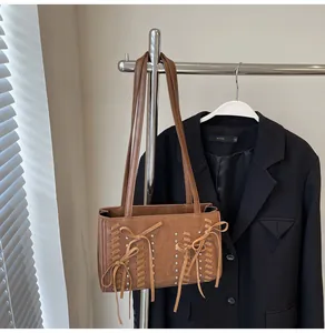 Detailed shot of a brown suede shoulder bag with ribbon bows and silver metal rivets