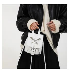 Détail du mini sac à dos blanc avec découpe papillon et boucle métallique décorative