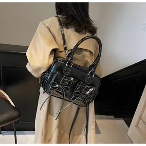 Detail of black glossy handbag with white contrast stitching and elegant bow design
