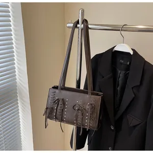 Detail of dark brown faux leather shoulder bag with rivet studs and bow ribbons