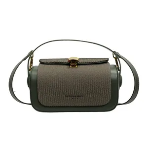 Détail du fermoir en métal doré en forme de coquillage sur un sac bicolore vert et marron