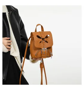 Détail du mini sac à dos en cuir marron avec motif papillon ajouré et anneau en métal argenté