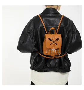 Mini sac à dos marron avec motif papillon ajouré porté avec une veste en cuir noir