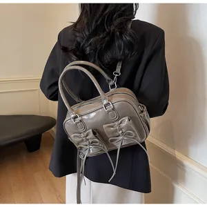 Detail showing bow decorations on a glossy brownish gray patent leather backpack