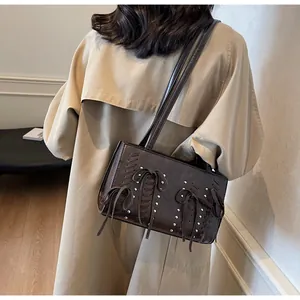Dark brown bow shoulder bag with silver studs and woven details on a model
