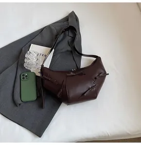 Détail d'un sac demi-lune en cuir chocolat avec d'élégants nœuds sur un costume gris