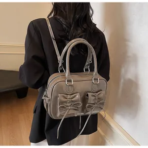 Macro detail of khaki pleated backpack with decorative bows and glossy finish