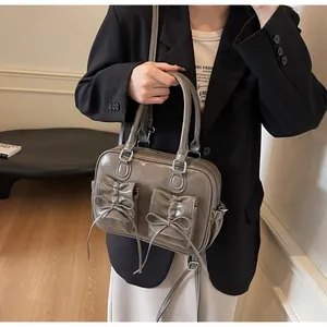 Detail of dark gray patent leather handbag with bow pockets and thin shoulder strap