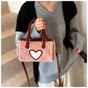 Detail van roze pluche Boston tas met witte hartpatch en rode leren handvatten