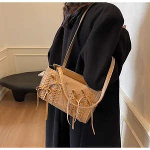 Detail of light brown suede shoulder bag with metallic rivets and bow tassels