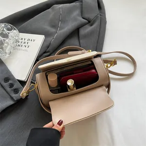 Sac à bandoulière cylindrique beige en cuir montrant l'intérieur avec des objets personnels