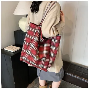 Red black white plaid tote bag with wide straps and gold detail shown on model