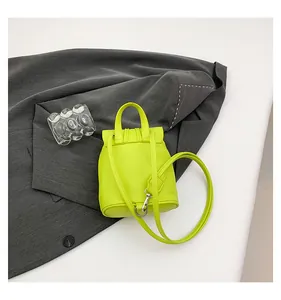 Détail de la texture cuir vert citron et des crochets métalliques sur le mini sac à main