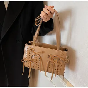 Detail showing faux suede shoulder bag with decorative bows and silver rivet accents