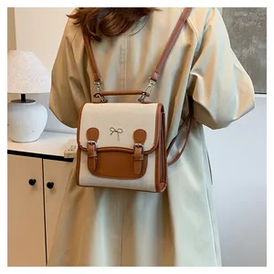 Detail of mini canvas and brown leather backpack with bow buckle and dual straps