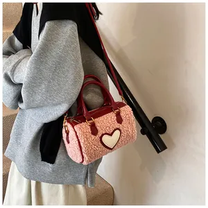 Detail van roze teddy fleece cilindertas met witte hartpatch en rode handvatten