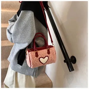 Detail van roze fleece handtas met wit hart en rode lederen schouderband
