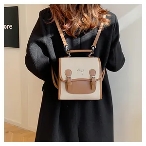 Detail of a mini canvas backpack with brown leather trim and a bow accent on the back