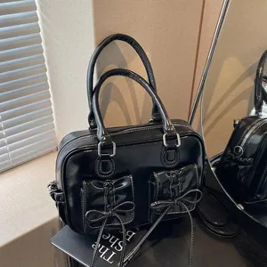 Glossy black bow handbag with white contrast stitching and dual front flap pockets