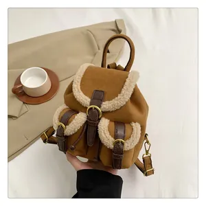Detail of plush brown suede backpack with cream fleece trim and gold metal buckles