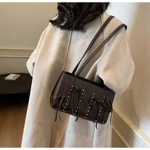 Detail of dark brown suede shoulder bag with bow accents and silver rivets on wool coat