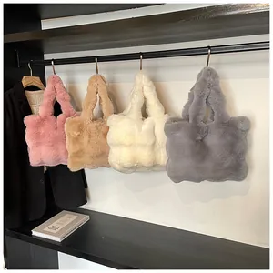 Detalle de bolsos tote de felpa en rosa, marrón, blanco y gris en estantes de exhibición