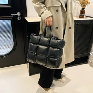 Borsa tote trapuntata nera dal design minimalista a quadri tenuta da una modella